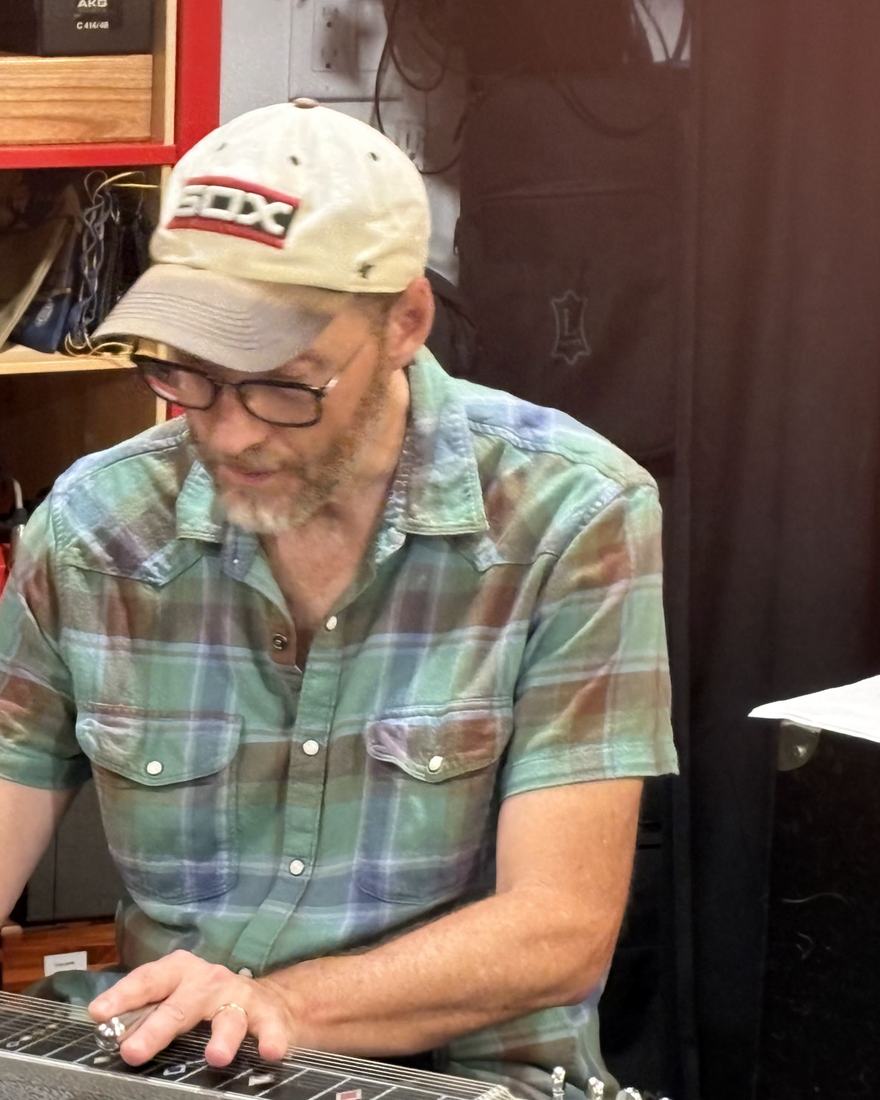 Parnell Flynn, in a ball cap and plaid shirt, playing pedal steel in the studio